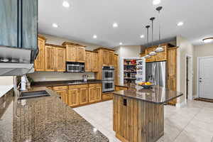 Kitchen featuring a center island, light tile patterned floors, stainless steel appliances, dark stone counters, and recessed lighting