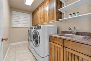 Washroom with washer and dryer, cabinet space, and light tile patterned floors