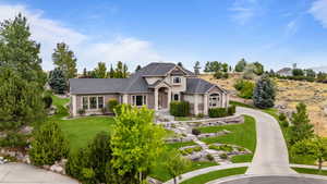 View of front of house with a front lawn, curved driveway, and brick siding