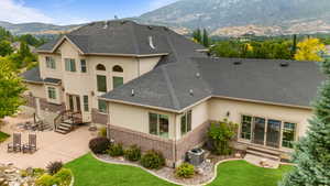 Back of property with stucco siding, a mountain view, a patio, and brick siding