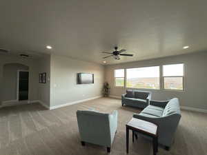 Living room with light colored carpet, recessed lighting, a ceiling fan, and arched walkways