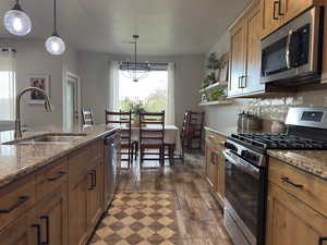 Kitchen featuring stainless steel appliances, dark wood finished floors, open shelves, and decorative light fixtures