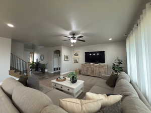 Living room featuring arched walkways, recessed lighting, ceiling fan, carpet flooring, and stairs