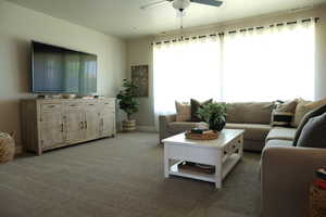 Living area with plenty of natural light, light carpet, and ceiling fan