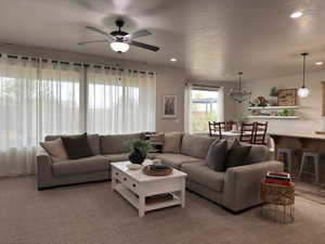 Living room with ceiling fan, a chandelier, a textured ceiling, and recessed lighting