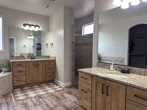 Bathroom featuring a walk in shower and two vanities