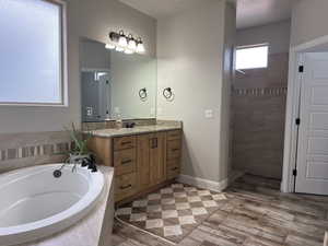 Full bath featuring vanity, a garden tub, a walk in shower, and wood tiled floors