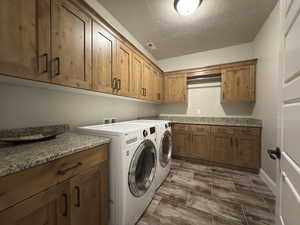 Washroom with cabinet space, washer and clothes dryer, wood finish floors, and a textured ceiling