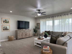 Carpeted living area with a textured ceiling, a ceiling fan, and recessed lighting