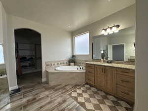 Bathroom featuring a bath, vanity, and a walk in closet