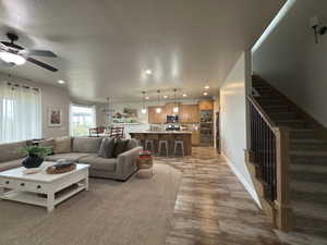 Living area with a textured ceiling, recessed lighting, ceiling fan, stairs, and wood finished floors