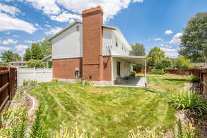 Rear view of house featuring brick siding, a fenced backyard, a patio, and a chimney