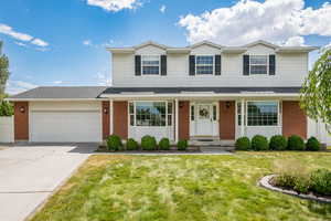 Traditional-style home featuring a garage, a front yard, brick siding, and concrete driveway