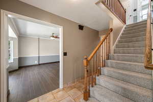 Stairway with healthy amount of natural light, ceiling fan, wood finished floors, and crown molding