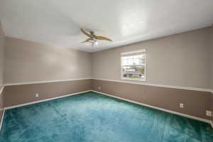 Carpeted empty room with ceiling fan and a textured ceiling