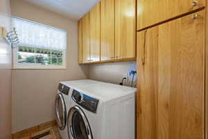 Laundry room featuring cabinet space, washing machine and clothes dryer, and light tile patterned flooring