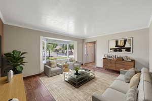 Living room with ornamental molding, wood finished floors, and a textured ceiling