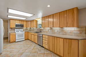 Kitchen with stainless steel appliances, backsplash, light stone countertops, light tile patterned floors, and recessed lighting