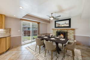 Dining area with ceiling fan, a fireplace, light tile patterned flooring, recessed lighting, and a textured ceiling