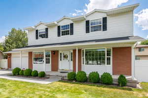 Traditional-style home with brick siding, a porch, driveway, and an attached garage