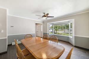 Dining room with wood tiled floors, a ceiling fan, and crown molding