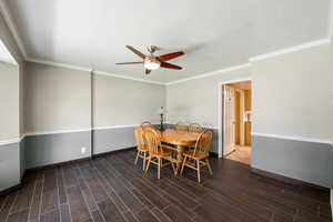 Dining room with a ceiling fan, crown molding, and wood finish floors