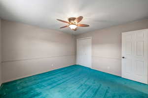 Unfurnished bedroom with carpet, a closet, and a ceiling fan