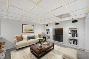Carpeted living area with built in shelves, a drop ceiling, and recessed lighting