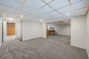 Finished below grade area with a drop ceiling, carpet flooring, recessed lighting, and stairway