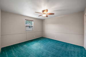 Carpeted spare room with a ceiling fan and a textured ceiling