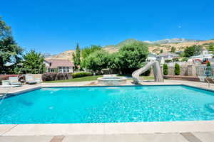 View of swimming pool with a water slide, a mountain view, a pool with connected hot tub, and a patio