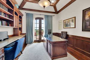 Office area featuring french doors, wainscoting, built in study area, wood finished floors, and arched walkways