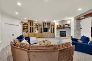 Living area featuring recessed lighting, light carpet, a stone fireplace, and crown molding