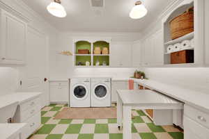 Washroom featuring cabinet space, washing machine and dryer, light floors, and ornamental molding