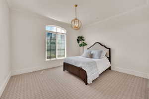 Carpeted bedroom featuring crown molding and a chandelier