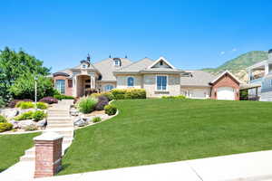 French country inspired facade featuring stone siding, a front yard, stairs, and roof with shingles