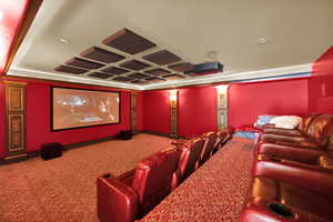 Carpeted home theater room with a raised ceiling and recessed lighting