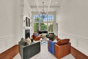 Living room with a decorative wall, a wainscoted wall, a fireplace, beam ceiling, and coffered ceiling