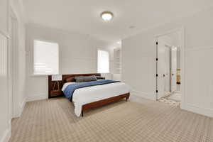 Bedroom with a wainscoted wall, ornamental molding, carpet floors, and multiple windows