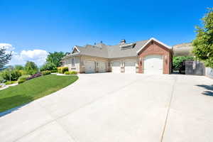 View of front of home featuring a garage, brick siding, concrete driveway, and a front lawn