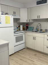 Kitchen with white appliances, light countertops, light wood finished floors, and light brown cabinetry