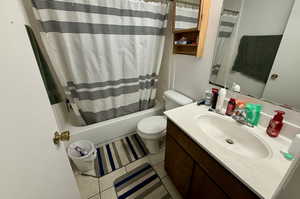 Bathroom with shower / bath combo, vanity, and light tile patterned flooring