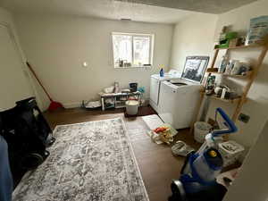 Laundry room featuring washing machine and dryer, dark wood-style flooring, and a textured ceiling