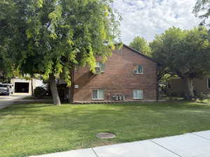 View of side of property with brick siding, a yard, and driveway