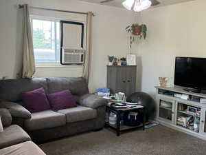 Carpeted living area with ceiling fan and cooling unit