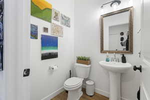 1/2 Bathroom featuring baseboards and wood finished floors near garage