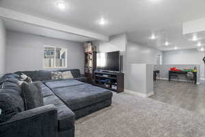 Living room featuring carpet, a textured ceiling, recessed lighting, and wood finished floors