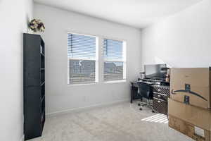Carpeted home office featuring baseboards