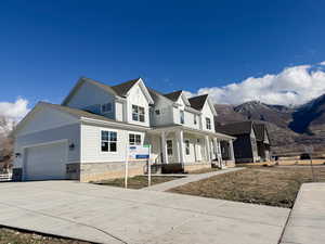 Modern farmhouse style home featuring a porch, board and batten siding, stone siding, driveway, and an attached garage