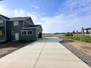 View of property exterior featuring a shingled roof, board and batten siding, a garage, and concrete driveway